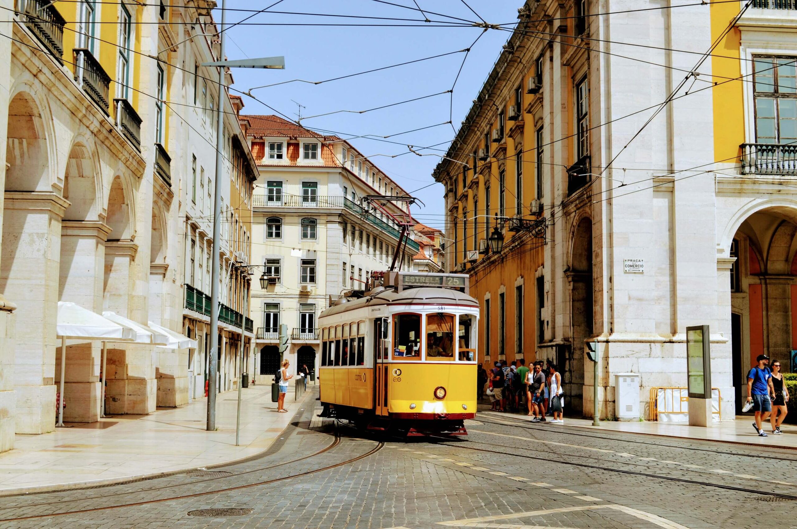 Bonde na cidade de Lisboa com pessoas ao redor de prédios antigos